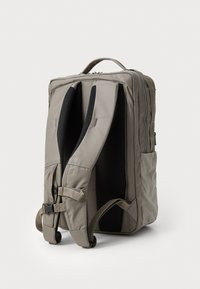 Gray fabric backpack with padded black straps, side pockets, and a top handle. Features a textured design and sturdy zippers.