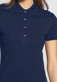 Polo shirt blu navy realizzato in tessuto testurizzato, con colletto a punta, chiusura con tre bottoni e un piccolo logo ricamato sul petto.