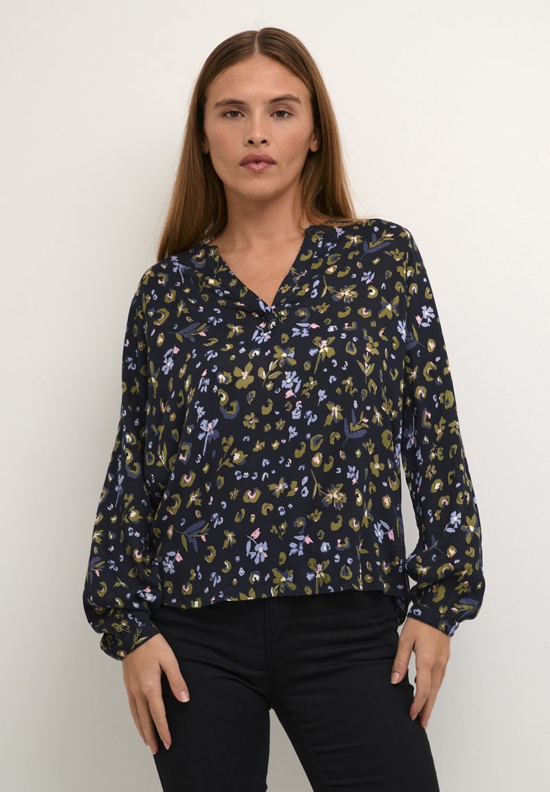 Blusa nera floreale con maniche lunghe, scollatura a v e vestibilità ampia. Presenta un motivo di fiori verdi, viola e gialli. Tessuto leggero.
