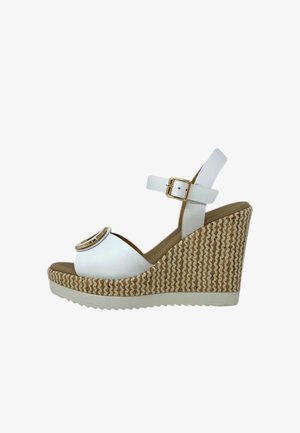 Sandali wedge bianchi con tacco a piattaforma. Presentano una punta arrotondata, una cinghia alla caviglia con una fibbia dorata e una base con texture intrecciata.