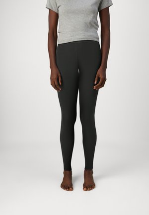 Svarte leggings laget av stretchy stoff, med en glatt, tettsittende design som strekker seg fra liv til ankler. Bærers med en grå kortermet topp.