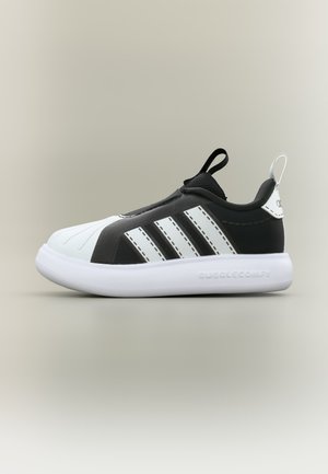 Schwarz-weißer Adidas-Sneaker mit weißer Sohle, drei weißen Streifen an der Seite und Zuglaschen an Zunge und Ferse.