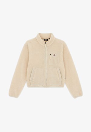 Veste en polaire beige avec un col haut, fermeture éclair à l'avant, deux poches avant et un petit logo sur la poitrine. Tissu doux et texturé.