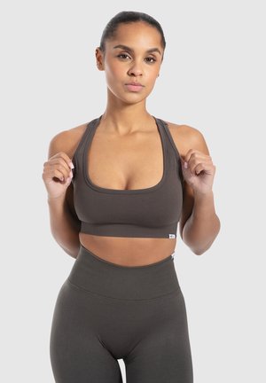 Bruine sportbh met een vierkante halslijn en brede banden, gemaakt van rekbaar materiaal. Gecombineerd met bijpassende hoge taille leggings.