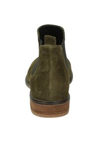 Bottine en suede vert olive avec des panneaux latéraux noirs, bout arrondi et semelle texturée marron. Elle présente une petite languette à l'arrière pour un enfilage facile.