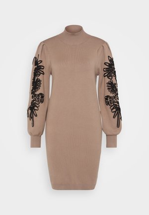 Strikket kjole i beige med høj hals. Lange ærmer har sort blomsterbroderi. Slim fit med ribbede manchetter og kant.