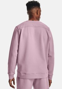 Felpa rosa con scollo a girocollo, polsini e orlo a coste, e una texture liscia. Il retro presenta un design di cucitura semplice e pulito.