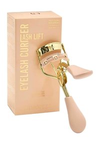 Recourbe-cils avec des accessoires en métal doré et des poignées en silicone rose. Accompagné d'une boîte rose clair portant un texte doré et des détails sur le produit.