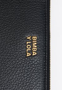 Cartera de cuero negro texturizado que presenta el logotipo dorado en relieve "BIMBA Y LOLA" y una cremallera dorada con costuras detalladas.
