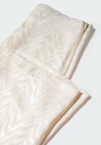 Tkanina w kolorze kremowym o subtelnym połysku, z tłoczonym wzorem. Przedmiot jest złożony, z widocznym detalem zamka błyskawicznego po jednej stronie.