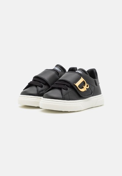 Schwarze Ledersneaker mit einer weißen Gummisohle, ausgestattet mit einem breiten schwarzen Riemen mit einem goldenen dekorativen Hardware-Akzent und schwarzen Schnürsenkeln.