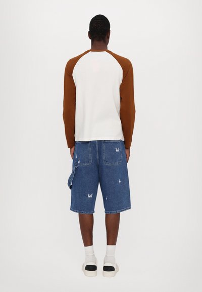 Long-sleeve shirt with brown raglan sleeves, white body. Paired with blue denim shorts featuring distressed details and pockets.
