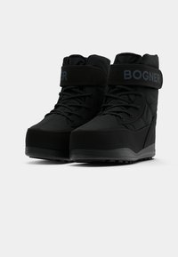Bottes de neige noires avec une surface rembourrée et texturée, dotées d'une sangle proéminente étiquetée "BOGNER" et d'un système de laçage à l'avant pour un ajustement sécurisé.