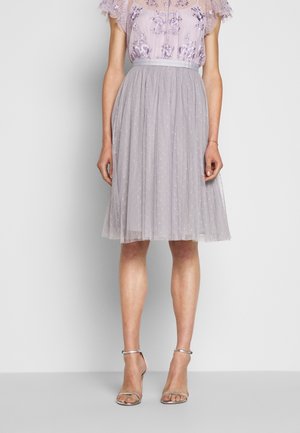 Lichtpaarse tule rok met een zachte textuur, geplooid ontwerp en polkadotdetails. Gecombineerd met zilveren sandalen met bandjes.