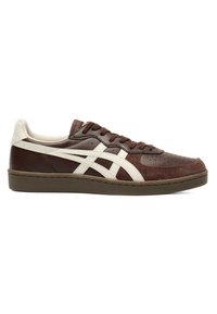 Baskets basses marron et beige avec des rayures blanches, des lacets et un bout perforé, vues de côté sur un fond blanc.