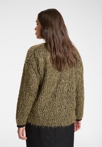 Teksturowany sweter w oliwkowej zieleni z luźnym wzorem dzianiny, z długimi rękawami i okrągłym dekoltem, pokazany od tyłu.