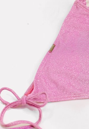 Haut de bikini en tissu rose pailleté avec lien latéral réglable et petite étiquette de marque rectangulaire dorée sur fond blanc.