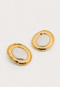 Cercei ovale cu ton de aur, având o textură ciocnită, cu un centru oval lucios din argint. Margini netede și un finisaj metalic contrastant.