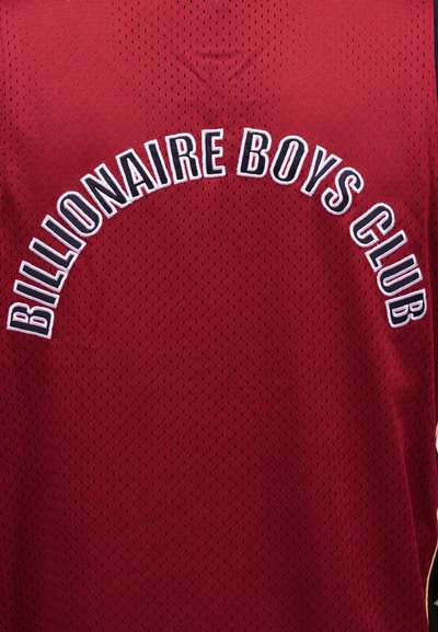 Μακρό ύφασμα από δίχτυ σε μαρουν απόχρωση με μαύρο κείμενο περιγραμμένο σε λευκό που γράφει «Billionaire Boys Club», καμπυλωμένο στο κέντρο.