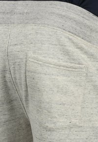 Hellgraue Jogginghosen mit einem gerippten Bund, weicher Textur und einer einzelnen Gesäßtasche mit einem dezenten gesprenkelten Muster.