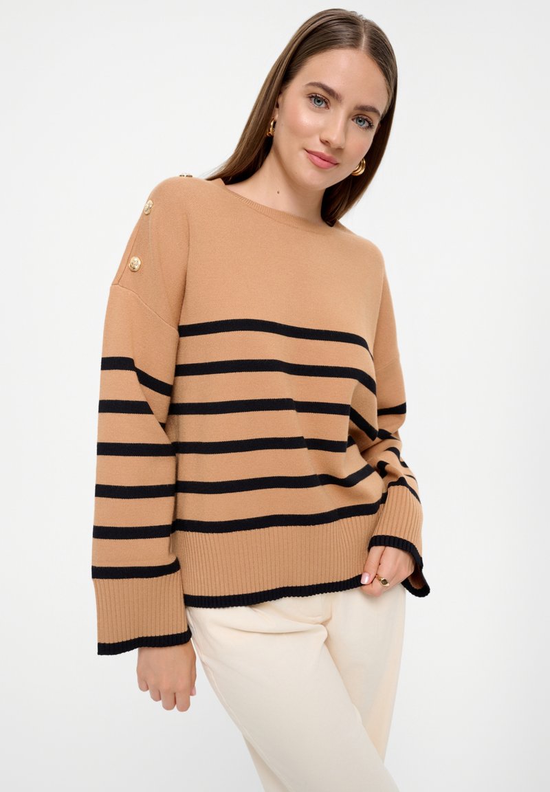 Beige gestreepte trui met horizontale zwarte strepen, geribde manchetten en gouden knopenaccenten op de schouder. Glad breisel.