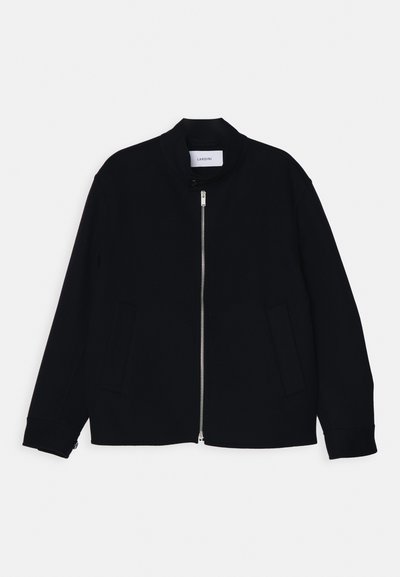 Czarna kurtka bomberka z kołnierzem stojącym, przednim zamkiem błyskawicznym i dwoma bocznymi kieszeniami. Wykonana z gładkiego materiału, z prążkowanymi mankietami.