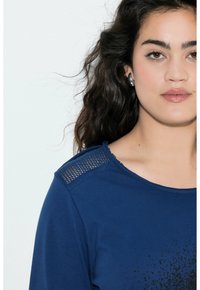T-shirt blu scuro con scollo rotondo, dettagli in rete testurizzata sulle spalle e un design a macchie nella parte inferiore anteriore.