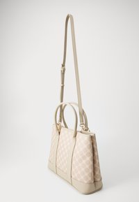 Sac tote beige avec un devant à motifs, forme structurée, base contrastée, doubles poignées et une bandoulière amovible et ajustable.