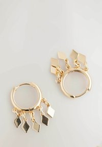 Orecchini a cerchio in oro presentano ciondoli a forma di diamante pendenti. Il design include metallo lucido con una finitura liscia e una forma circolare.