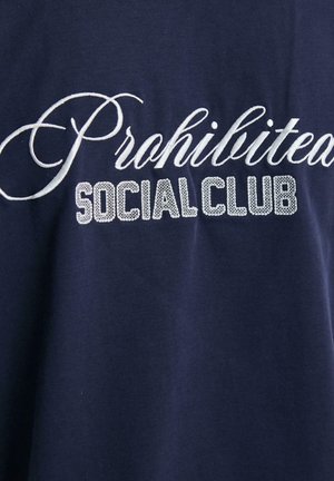 Mørkeblå bomull T-skjorte med brodert hvit skrift "Prohibited" og blokkbokstaver "SOCIAL CLUB" med en teksturert overflate.
