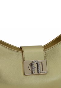Bolso de mano de cuero dorado con forma curva, que presenta un cierre metálico adornado con rhinestones que destacan un diseño de logo. Textura suave.
