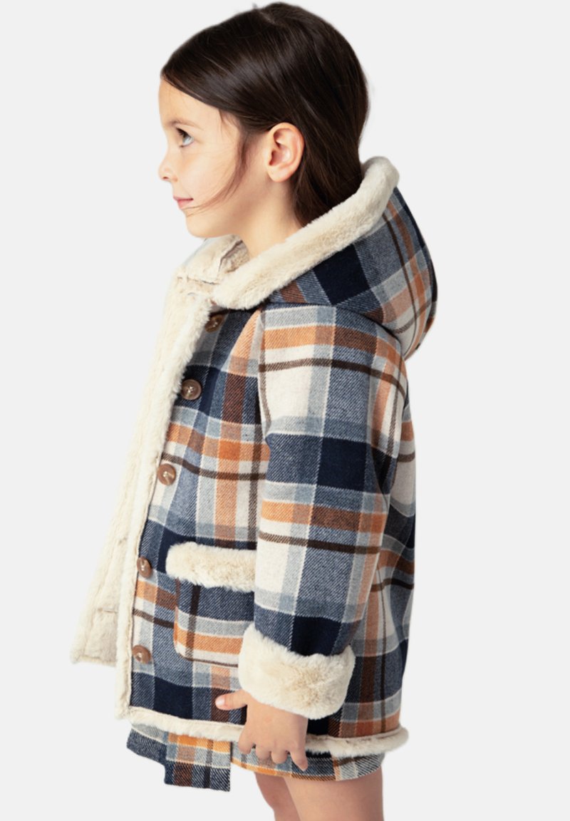Cappotto in pile a quadri nei colori navy, crema e ruggine, con cappuccio foderato in pelliccia sintetica, chiusure a bottoni e tasche laterali. Silhouette boxy e texture confortevole.