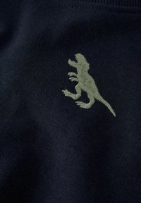 Sweat-shirt bleu marine foncé avec une broderie texturée de dinosaure vert sur la poitrine. Tissu doux avec un col rond classique.