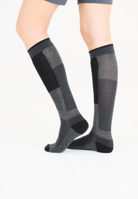 Knästrumpor i olika nyanser av grått, med en lapptäckedesign som har räfflad textur och en slät tådel.