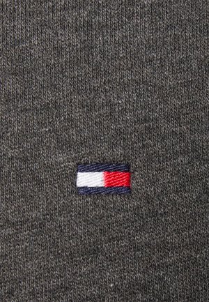 Grauer Strickstoff mit einem kleinen rechteckigen Logo mit horizontalen Streifen in Weiß, Rot und Marineblau.