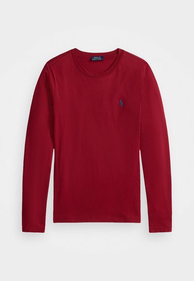 Červená dlhá rukávová košeľa z bavlny. Má okrúhly výstrih a malú modrú polo značku na ľavej hrudi. Hladká textura, neformálny dizajn.