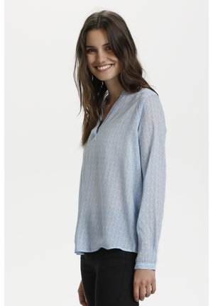 Blouse bleu clair avec un motif géométrique de feuilles, manches longues, encolure en V et ourlet légèrement arrondi, fabriquée à partir d'un tissu léger.