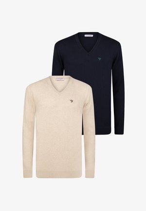 Twee v-hals truien, één in crème en één in marineblauw, met lange mouwen en een klein vogelembleem op de borst. Beide zijn gebreid.