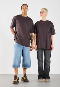 Overdimensionerede mørkeblå t-shirts, blå posede jeans og grå denim, parret med multicolor sneakers og lyse klipklapper.