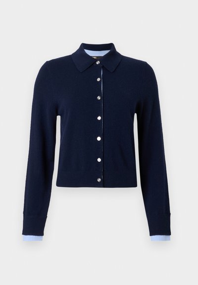 Cardigan bleu marine à manches longues avec boutons argentés, col polo, et tissu à carreaux bleu clair visible aux poignets et à la doublure du col.