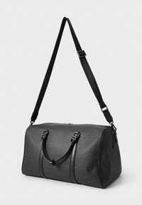 Mala de viagem preta com design texturizado, apresentando o nome da marca num padrão repetido, acabamentos em pele, duas alças e uma correia ajustável.