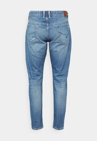 Jeans de denim azul claro com um corte slim, apresentando uma cintura média, dois bolsos traseiros e ligeira desgastagem no tecido.
