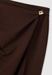 Tessuto marrone drappeggiato con una texture liscia, caratterizzato da un accento metallico dorato in vita, che crea un effetto drappeggiato.