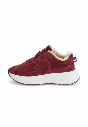 Baskets en suede rouge avec une doublure beige en peluche, dotées d'une semelle blanche épaisse au fini texturé et d'un logo circulaire bien en évidence sur le côté.