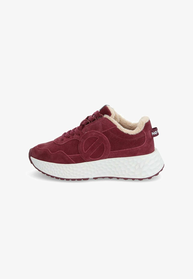 Baskets en suede rouge avec une doublure beige en peluche, dotées d'une semelle blanche épaisse au fini texturé et d'un logo circulaire bien en évidence sur le côté.