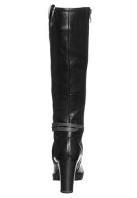 Botas de cuero negro hasta la rodilla con un tacón curvado, cierre de cremallera y un delgado acento de tirante negro en el tobillo. Textura suave, sin patrones.
