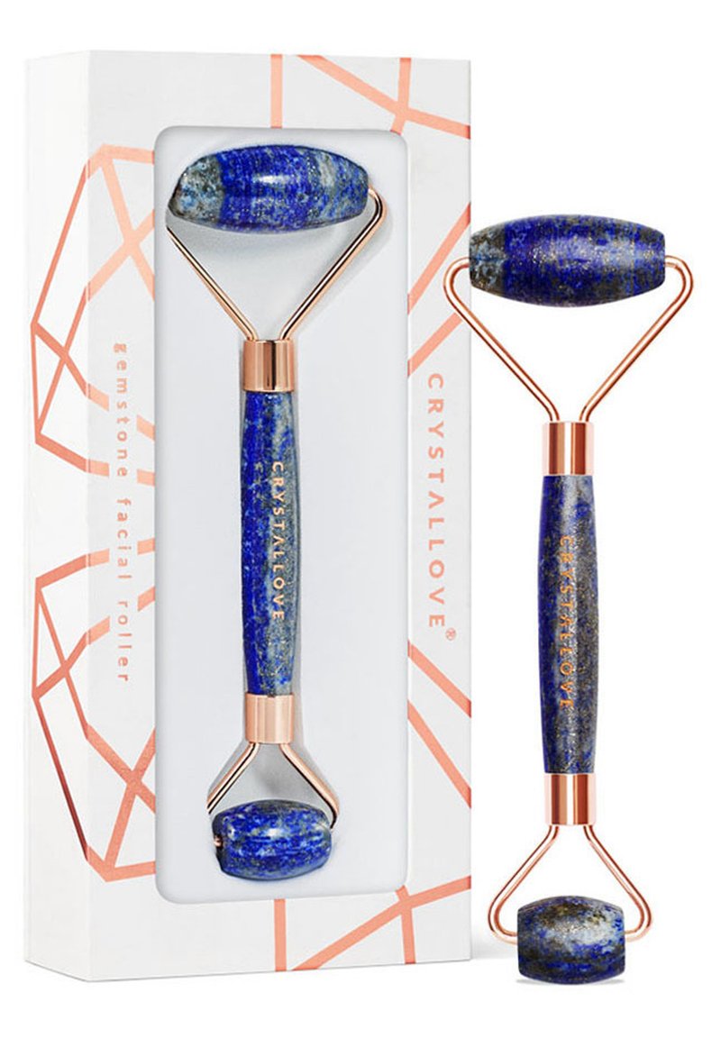 Niebieski kamienny roller do twarzy z wypolerowanymi końcówkami z lapis lazuli, złotymi metalowymi akcentami i charakterystycznym geometrycznym opakowaniem.