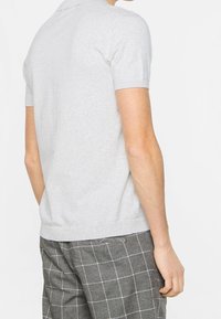 Polo gris de manga corta con cuello clásico y ribete en el dobladillo. Tejido suave y ligero. Diseño ligeramente ajustado.