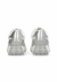 Les baskets blanches présentent un talon texturé argenté et une tige lisse et brillante. La semelle extérieure est dotée de motifs hexagonaux antidérapants en gris clair.