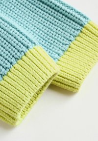 Poignets tricotés en bleu clair et vert vif, présentant un motif texturé avec des détails côtelés. Matière en fil doux avec une apparence chaleureuse.